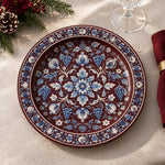 Burgundy charger plate featuring blue and white floral garland around a blossom medallion