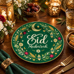 Green charger plate with gold trim featuring Eid script, crescent and lanterns among olive leaves