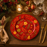 * Red holiday under plates styled on a beautifully set Christmas dinner table with candles and pine cones.