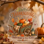 Clear acrylic hanging wall decor showing a wooden wheelbarrow of pumpkins, lanterns, plaid blanket, and autumn leaves.