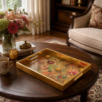 Diwali Floral Paisley Tray with Lotus & Diyas - Gold Frame - Minti Home displayed on a dining table with a porcelain teapot and fresh flowers, vintage cabinet in background.