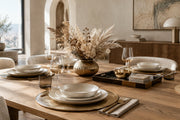 Sophisticated 2026 dining table styling featuring layered metallic charger plates, a decorative tray, and a fluted vase.