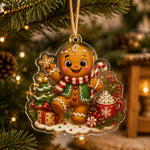 Gingerbread man acrylic hanging decor with a candy cane and Christmas tree hanging on a pine branch with warm lights.
