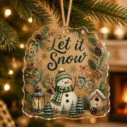 Let it Snow clear acrylic hanging ornament with a snowman, lantern, and pine branches hanging from a tree.