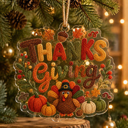 Thanksgiving acrylic hanging ornament with a textured faux-knit turkey and pumpkins, displayed on a festive green branch.