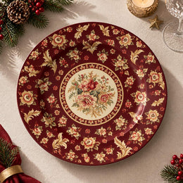 Burgundy charger plate with gold trim featuring a rose medallion and scattered fleur-de-lis sprigs