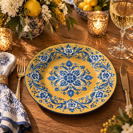 Golden yellow charger plate featuring a cobalt blue floral medallion and scroll border