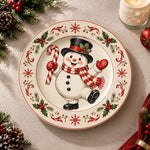 White charger plate with gold trim featuring a snowman framed by holly leaves and red berries