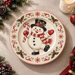 White charger plate with gold trim featuring a snowman framed by holly leaves and red berries
