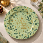 Sage green charger plate with gold trim featuring Arabic calligraphy among gold sprigs and lanterns