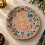Blush pink charger plate with gold trim featuring calligraphy, a crescent and a mosque