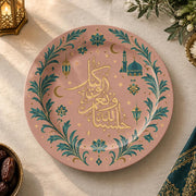 Blush pink charger plate with gold trim featuring calligraphy, a crescent and a mosque