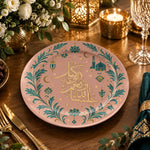 Blush pink charger plate with gold trim featuring calligraphy, a crescent and a mosque