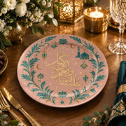 Blush pink charger plate with gold trim featuring calligraphy, a crescent and a mosque