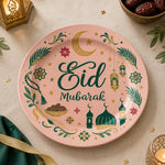 Pink charger plate with gold trim featuring Eid script, a mosque and a lantern among leaves