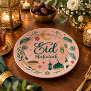 Pink charger plate with gold trim featuring Eid script, a mosque and a lantern among leaves
