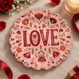 Pink scalloped plate with deep wine LOVE letters among oxblood flowers