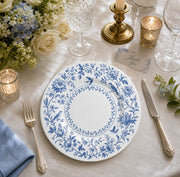 * Romantic wedding banquet table setting featuring elegant white floral charger plates under formal dinnerware.