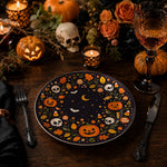 * Halloween charger plate with pumpkins, skulls, and bats on a dark dinner table setting with gold cutlery.
