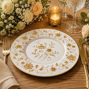 * Gold floral charger plate styled on a dinner table with gold flatware, white roses, and a lace napkin.