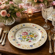* Vintage floral under plate set on a linen tablecloth with elegant gold cutlery and fresh flowers for a dinner party.