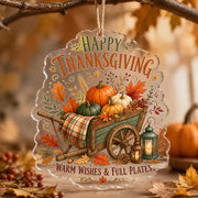 Clear acrylic hanging wall decor showing a wooden wheelbarrow of pumpkins, lanterns, plaid blanket, and autumn leaves.