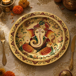 Gold Diwali charger plate featuring a jeweled Lord Ganesha portrait surrounded by red and green paisley and lotus borders.

Plate type: electroplated