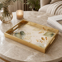 Sage Botanical Cream Gold Decorative Tray with Abstract Leaves and Gold Frame | Minti Home on a coffee table, featuring UV-printed artwork on tempered glass with an electroplated frame and matching handles.