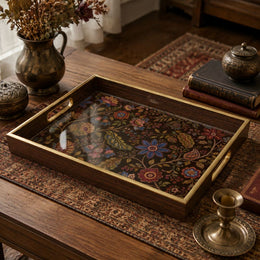 Bohemian Floral Serving Tray with Dark Wood Frame, Wildflower on a dark wood coffee table, featuring jewel-toned dahlias, marigolds, and bellflowers on a deep umber ground in a Jacobean-inspired vine, displayed on a tempered glass base with an electroplated warm-wood frame and matching handles.