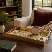 Christmas Poinsettia Holly Glass Serving Tray with Gold Frame, 40x30cm styled on a console table with a ceramic mug and books beside a brass lamp.