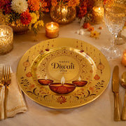 Gold Diwali charger plate with three lit red diya oil lamps, 