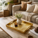 Fingerprint Art Glass Serving Tray – Gold Topographic styled on a console table with a ceramic mug and books beside a brass lamp.