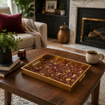 Sports Heritage Glass Serving Tray – Burgundy Gold Icons displayed on a dining table with a porcelain teapot and fresh flowers, vintage cabinet in background.