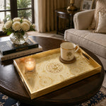 State of Qatar Glass Serving Tray – Gold Scrollwork Crest displayed on a dining table with a porcelain teapot and fresh flowers, vintage cabinet in background.