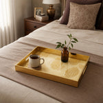 Fingerprint Art Glass Serving Tray – Gold Topographic displayed on a dining table with a porcelain teapot and fresh flowers, vintage cabinet in background.
